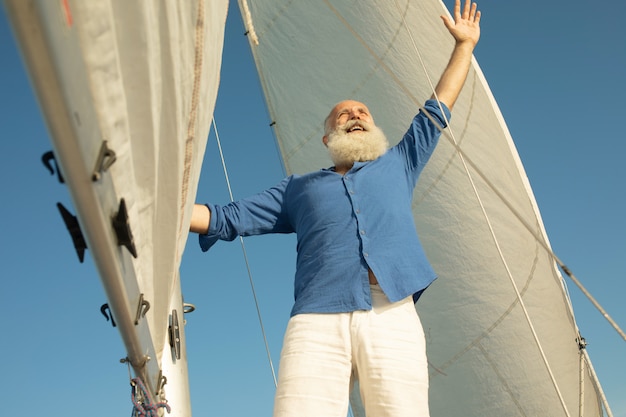 Homme senior barbu sur voilier ou yacht flottant sur le lac.