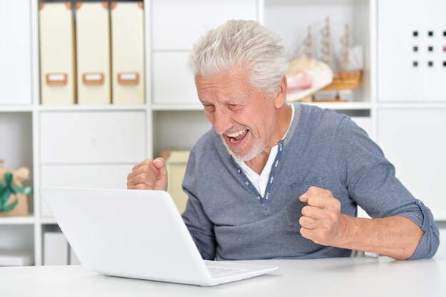 Homme senior émotionnel à l'aide d'un ordinateur portable