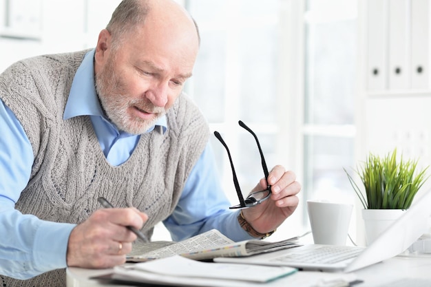 Homme senior émotionnel lisant le journal à la maison