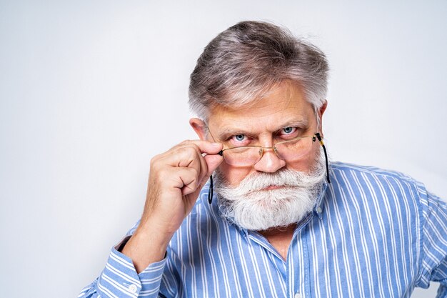 Homme senior excentrique avec portrait d'expression drôle isolé sur blanc