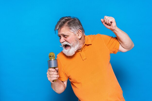 Homme senior excentrique avec portrait d'expression drôle isolé sur bleu