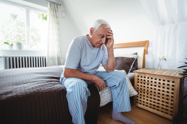 Homme senior frustré, assis sur le lit