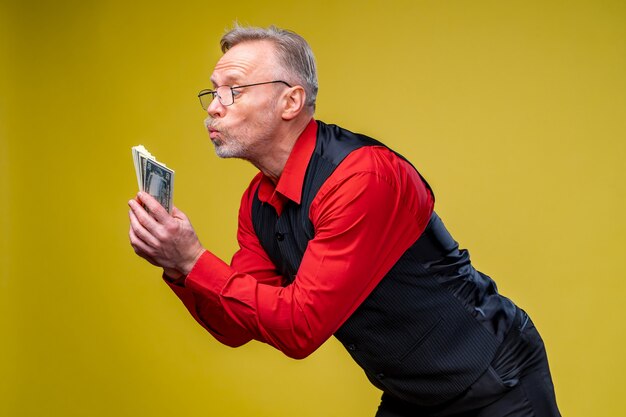 Un homme senior a gagné à la loterie. Fan d'argent près du visage du vieil homme. Jour de chance. Émotions humaines et expressions faciales.