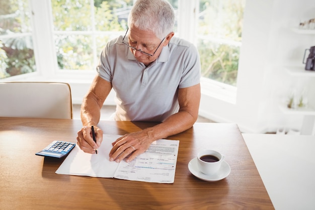 Homme senior inquiet avec des documents fiscaux à la maison