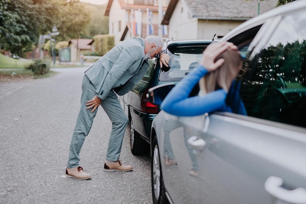 Homme senior et jeune femme se disputant après un accident de voiture.