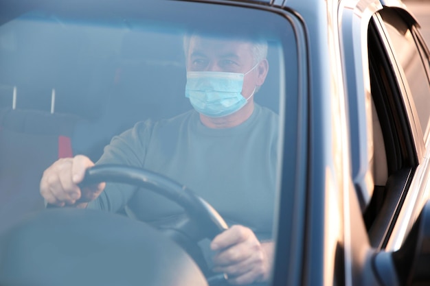 Homme senior avec masque médical dans la voiture Protection contre les virus