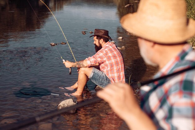 Homme senior mature avec un ami pêchant Vacances d'été Gens joyeux heureux Hommes barbus attrapant du poisson Pêcheur avec canne à pêche Activité et passe-temps