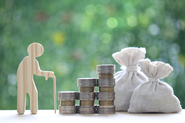 Homme senior et pile de pièces d'argent sur fond vert naturel