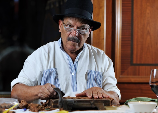 homme senior plus âgé fabriquant une cigarette cubaine de luxe faite à la main
