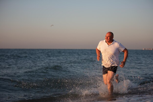 Homme senior qui court sur la plage Courir au resort