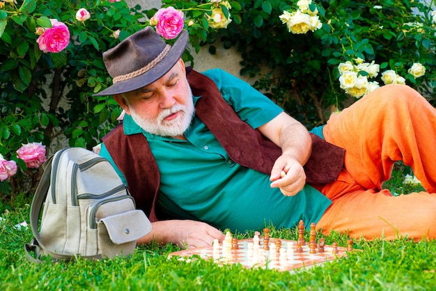 Homme senior se détendre dans le jardin. Jeu d'échecs. Jardinier mature bénéficiant dans le jardin.