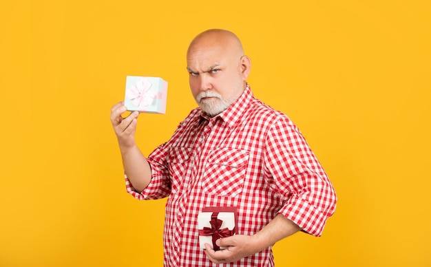 Homme senior sérieux avec boîte cadeau pour anniversaire