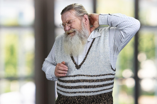 Homme senior stressé touchant sa main sur la nuque. Notion de douleur.