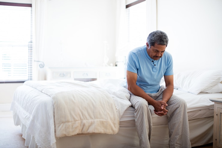 Photo homme senior tendu assis sur le lit