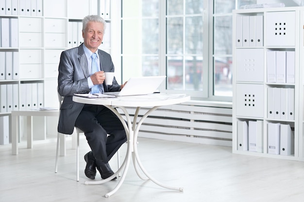 Homme senior en tenue de soirée à l'aide d'un ordinateur portable au bureau