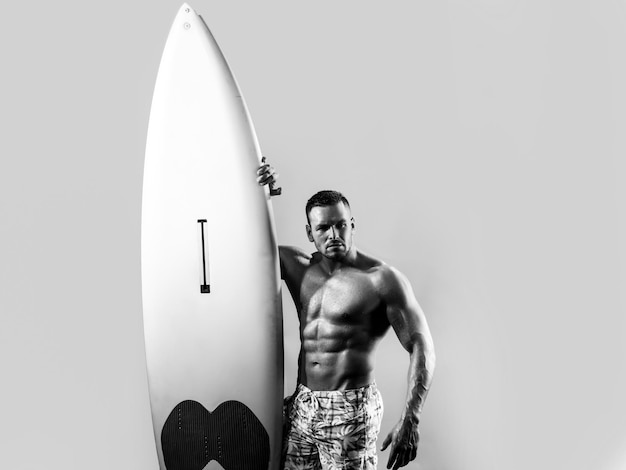 Homme serfer avec planche de surf Concept de passe-temps de surf Mode de vie actif Vacances d'été de loisirs de plage pour hommes Surfeur musclé sexy avec une planche de surf Garçon d'été isolé sur bleu