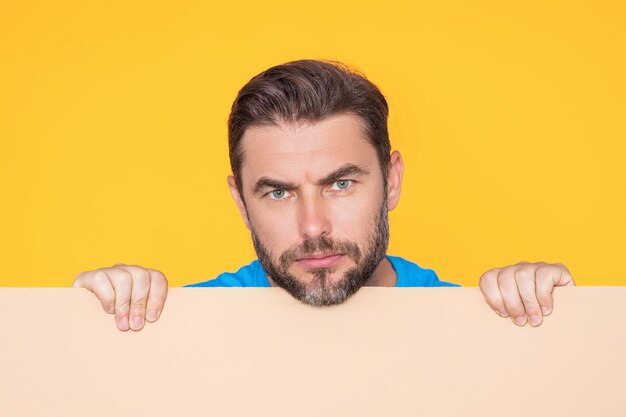 Homme sérieux avec une bannière vierge posant isolé sur fond de studio portrait d'un homme séduisant h