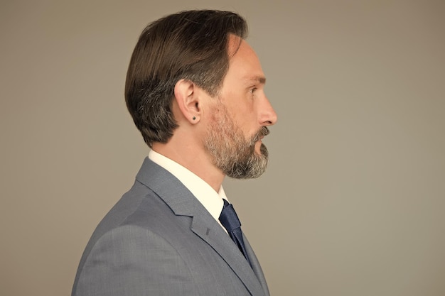 Homme sérieux bien soigné avec barbe en costume vue latérale concept de services de salon de coiffure