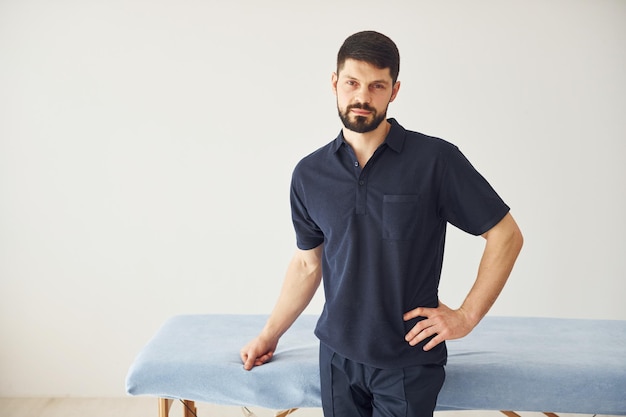 Homme sérieux en chemise debout à l'intérieur sur fond blanc