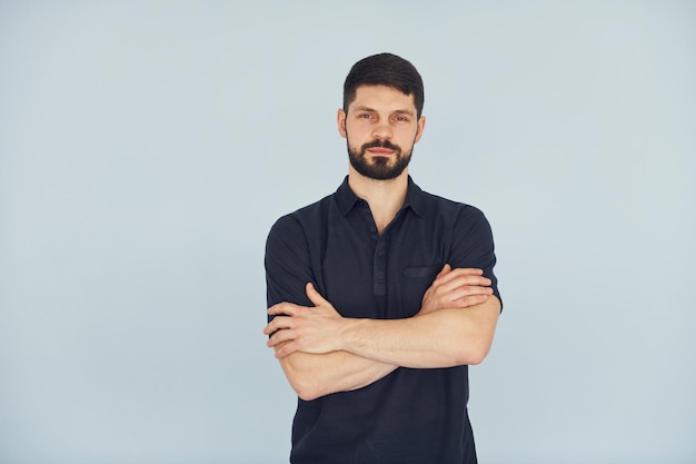 Homme sérieux en chemise debout à l'intérieur sur fond blanc