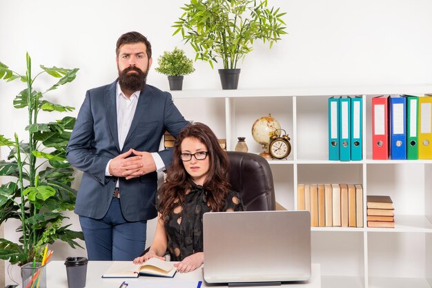 Homme sérieux en costume debout sur une femme de carrière travaillant chez des employés de bureau