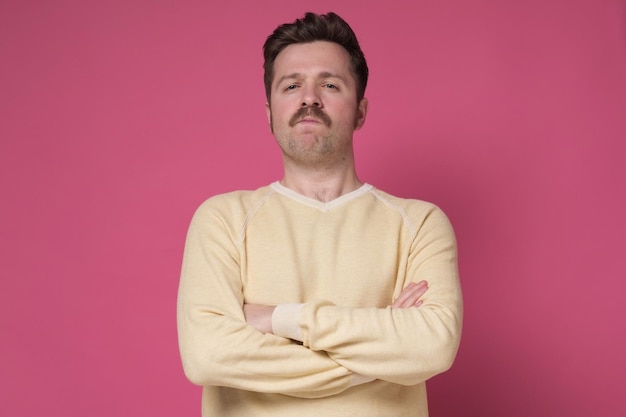 Homme sérieux avec moustache avec les mains jointes sur fond rose