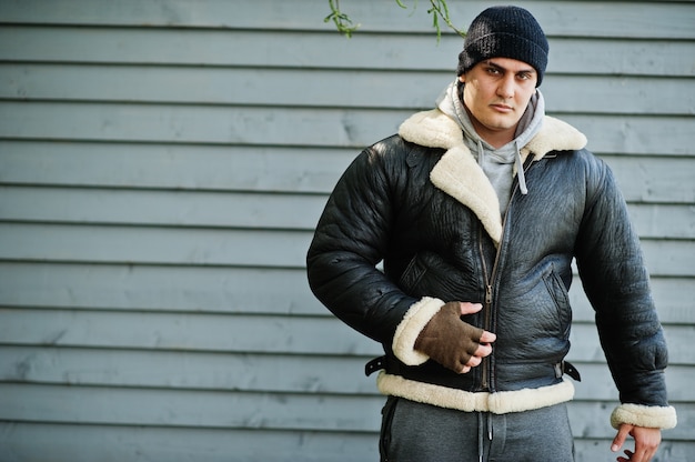 Homme sérieux portant une veste en cuir et un chapeau noir