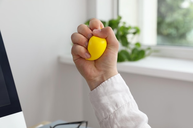 Homme serrant une balle anti-stress jaune en gros plan de bureau