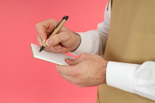 Homme de serveur écrire la commande dans un cahier sur fond rose