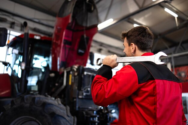 Photo un homme de service avec une clé à outils prêt à réparer le tracteur.