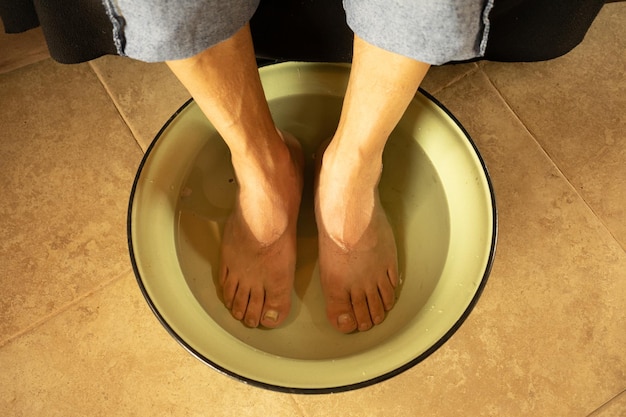 Un homme avec ses pieds dans un bol d'eau chaude