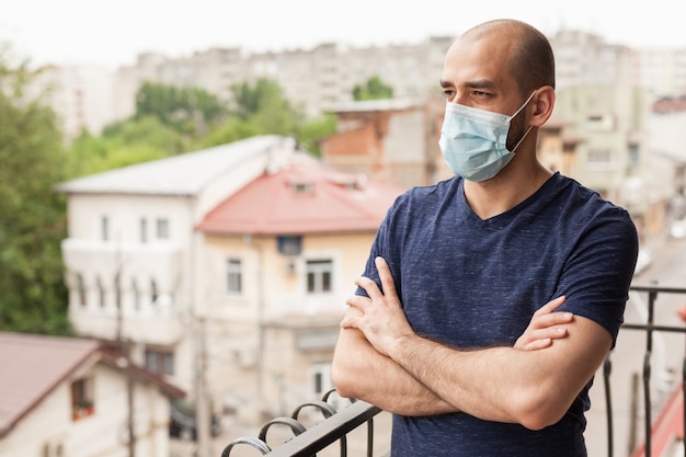 Homme seul sur balcon portant un masque de protection pendant le verrouillage du coronavirus.