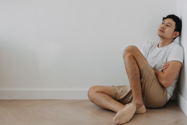 Un homme seul et déprimé assis au coin de la pièce.