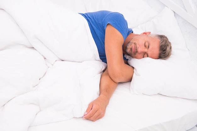 Homme sexy allongé sur le lit avec des oreillers moelleux à la maison Matin parfait Conseils pour mieux dormir la santé masculine Profiter du temps à la maison Se détendre dans la chambre rêver un homme Jour de sommeil Matin d'un nouveau jour