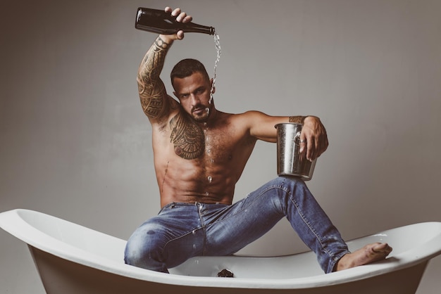 Homme sexy sur la baignoire avec champagne célébrant Noël ou anniversaire fête de sexe privée