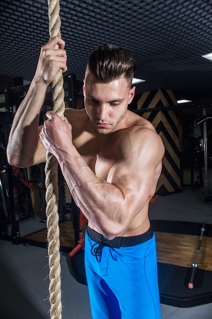 Homme sexy dans la salle de gym avec des haltères