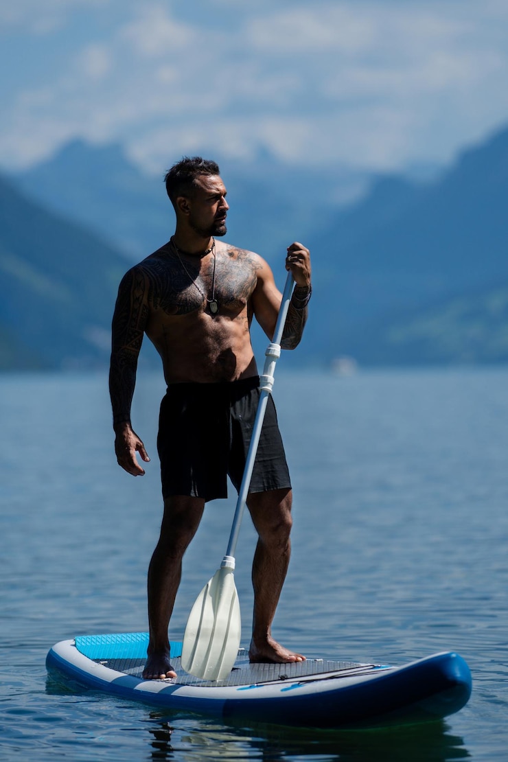 Photo un homme sexy avec une planche à pagaie un homme à la planche à gaule un homme musclé et fort