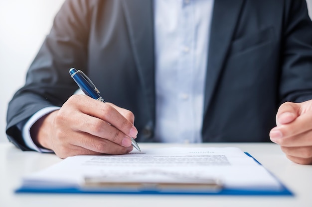 Homme signant des documents contractuels après avoir lu un homme tenant un stylo et approuvé le rapport d'activité Loi sur les accords contractuels et concepts d'accord