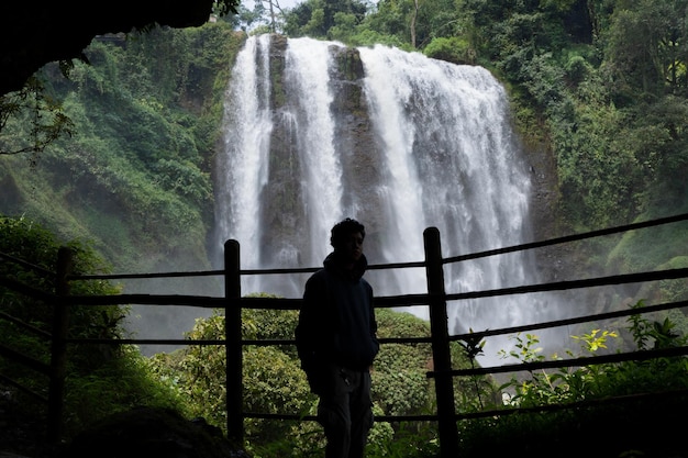 Homme de silhouette sur la caverne devant la grande chute d'eau Semarang Central Java