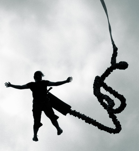 Photo l'homme de la silhouette fait un saut en bungee contre le ciel