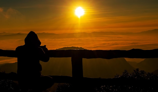 Homme de silhouette prenant des photos de coucher du soleil