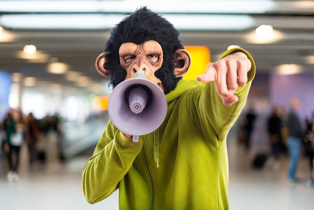 Un homme de singe criant par mégaphone sur un fond non focalisé