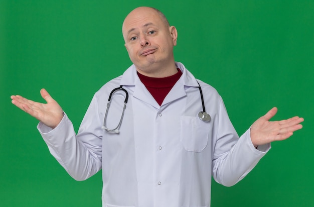 Homme slave adulte confus en uniforme de médecin avec stéthoscope gardant les mains ouvertes