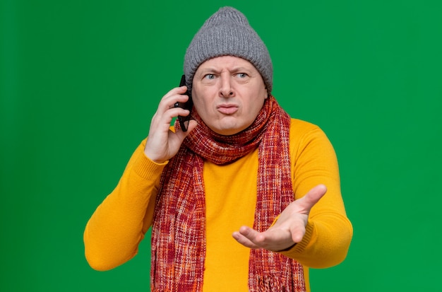 Homme slave adulte ignorant avec un chapeau d'hiver et une écharpe autour du cou parlant au téléphone