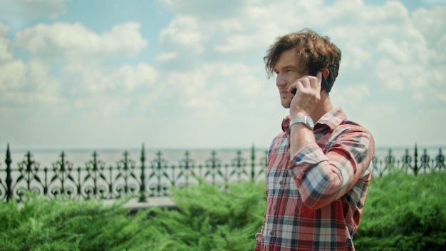 Homme avec smartphone debout sur le chemin dans le parc Guy appelant un téléphone portable à l'extérieur