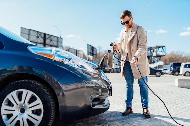 Un homme avec un smartphone plie le câble du chargeur de voiture