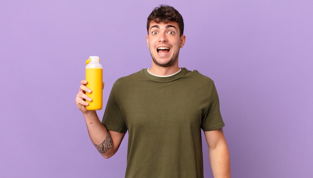 Homme avec smoothy à l'air heureux et agréablement surpris, excité par une expression fascinée et choquée