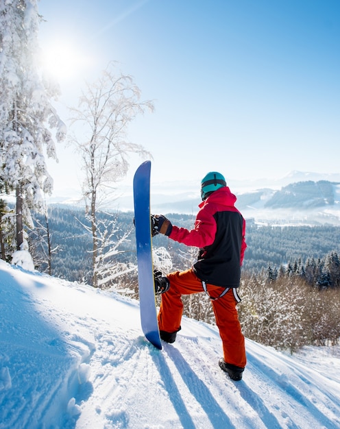 Homme avec un snowboard debout sur une montagne