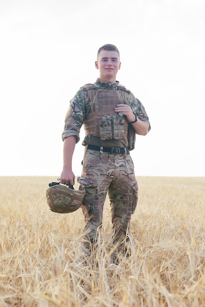 Homme soldat debout contre un champ. Portrait d'un soldat militaire heureux dans un camp d'entraînement. Soldat de l'armée américaine dans la mission. guerre et concept émotionnel.