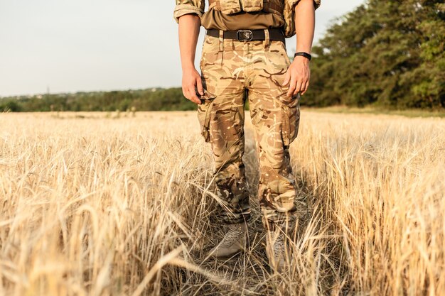 Homme soldat debout contre un champ. Portrait d'un soldat militaire heureux dans un camp d'entraînement. Soldat de l'armée américaine dans la mission. guerre et concept émotionnel.